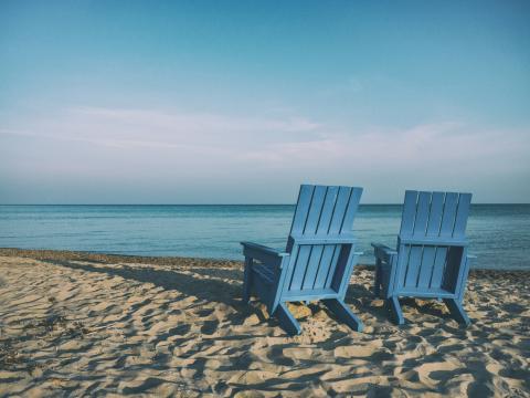 two blue beach chairs near body of water by Aaron Burden courtesy of Unsplash.